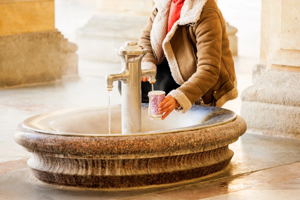 Žena si nabírá do hrnku pramen. 