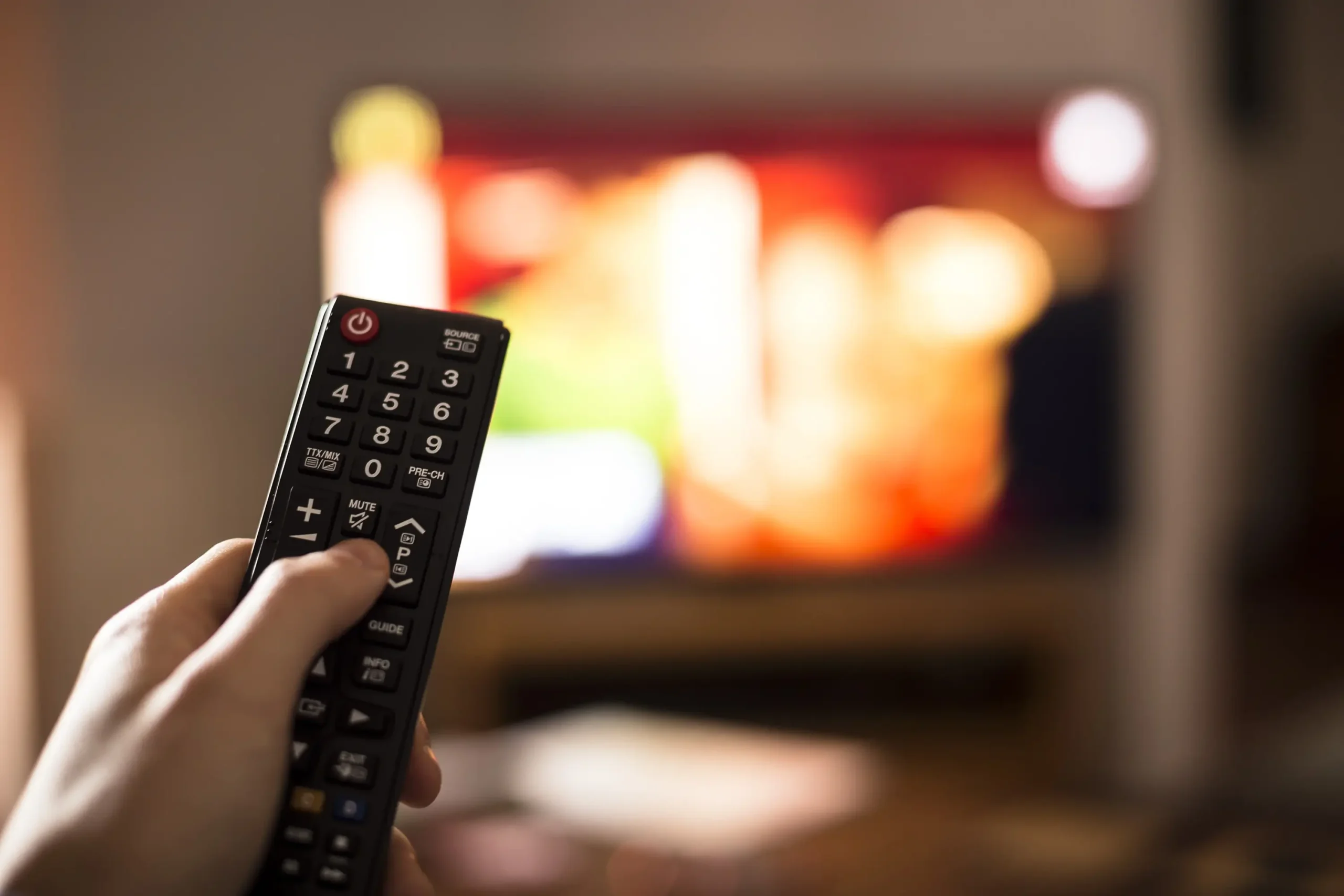 Ruka drží televizní ovladač. 