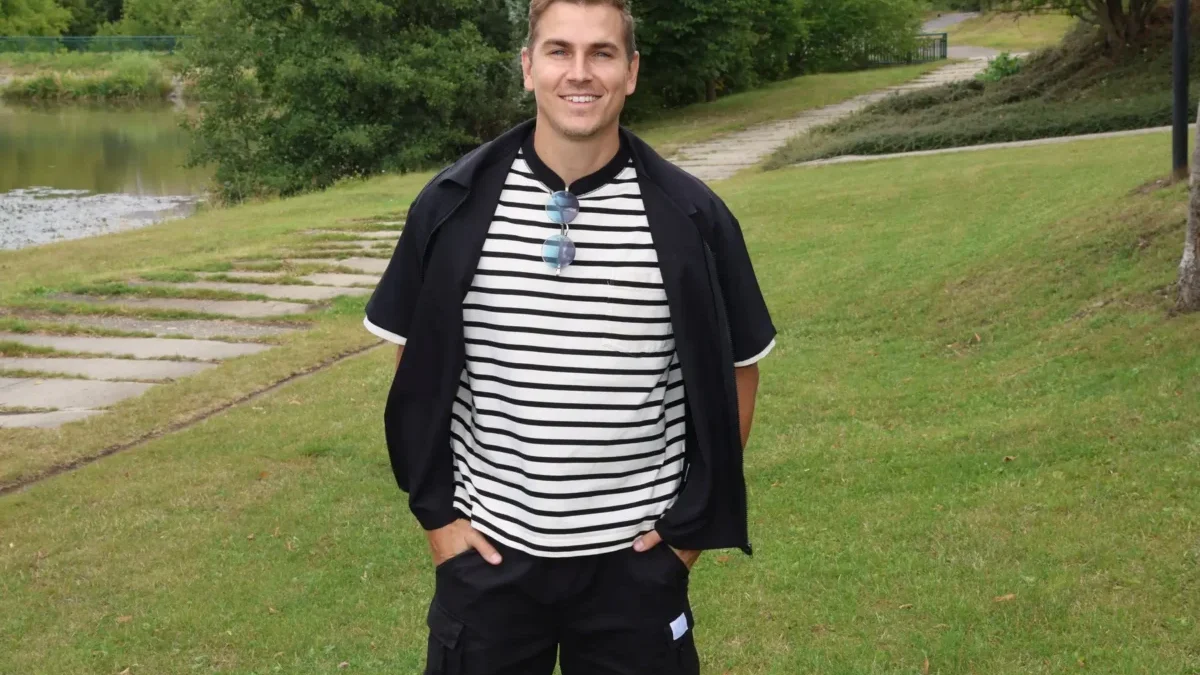 David Gránský stojí na louce a má ruce v kapsách.