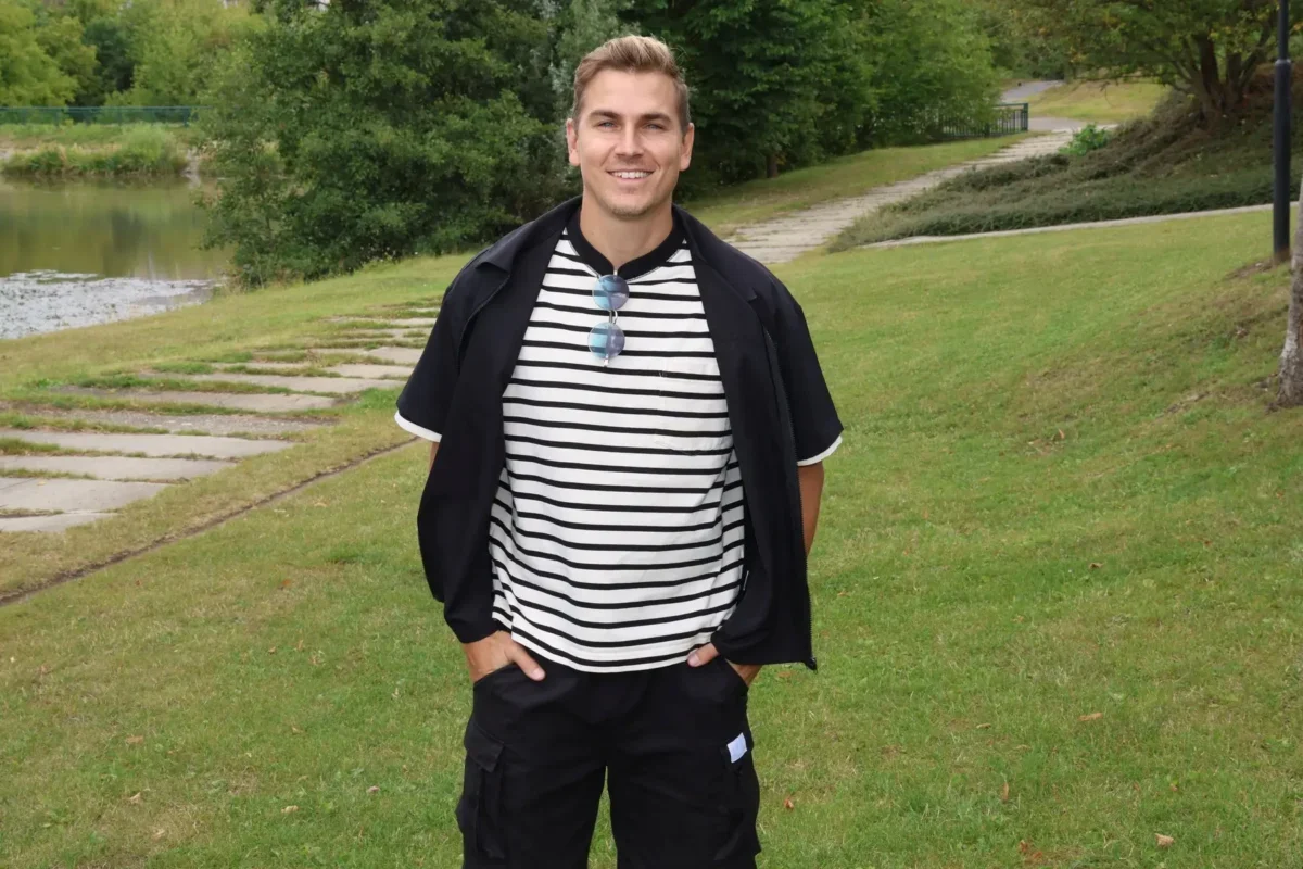 David Gránský stojí na louce a má ruce v kapsách.