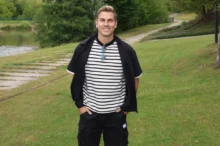 David Gránský stojí na louce a má ruce v kapsách.