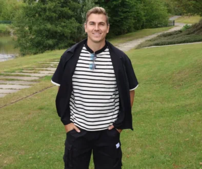 David Gránský stojí na louce a má ruce v kapsách.