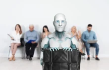 Robot sedí před lidmi.
