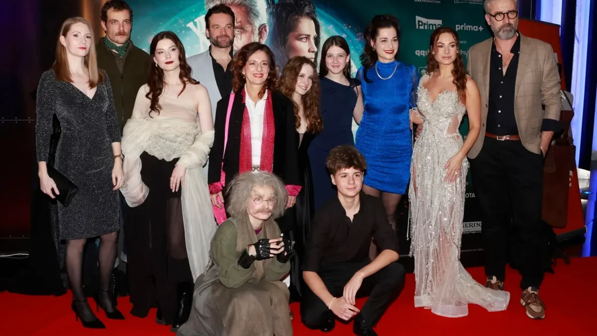 Herci stojí na červeném koberci.