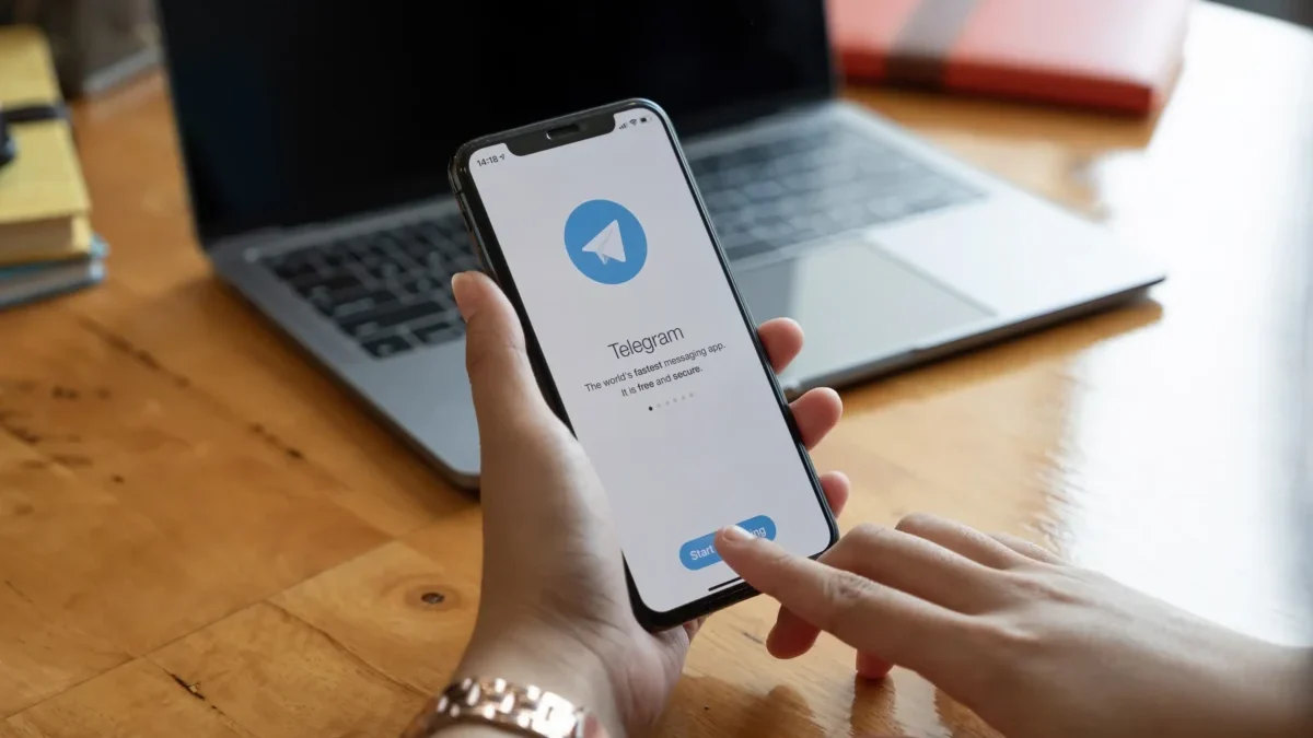 Člověk v ruce drží telefon s Telegramem.
