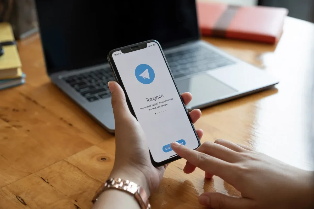 Člověk v ruce drží telefon s Telegramem.
