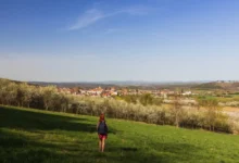 Žena kráčí loukou.