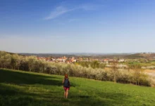 Žena kráčí loukou.