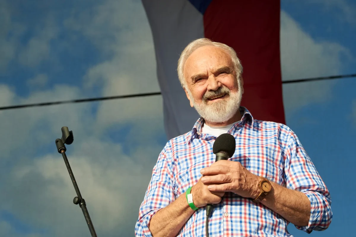 Zdeněk Svěrák stojí na pódiu a usmívá se.