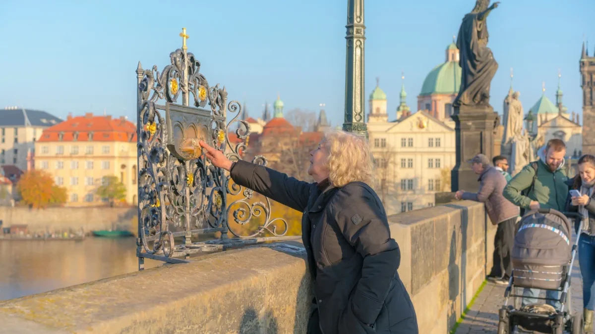 Žena sahá na část Karlova mostu.