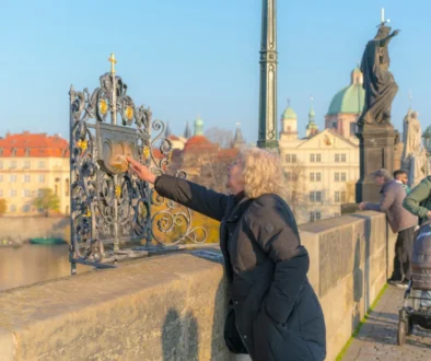 Žena sahá na část Karlova mostu.
