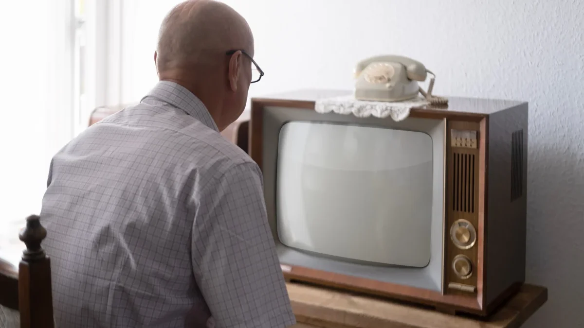 Starý muž sedí před TV.