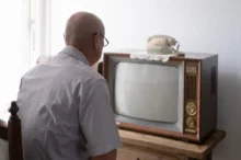 Starý muž sedí před TV.