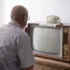 Starý muž sedí před TV.