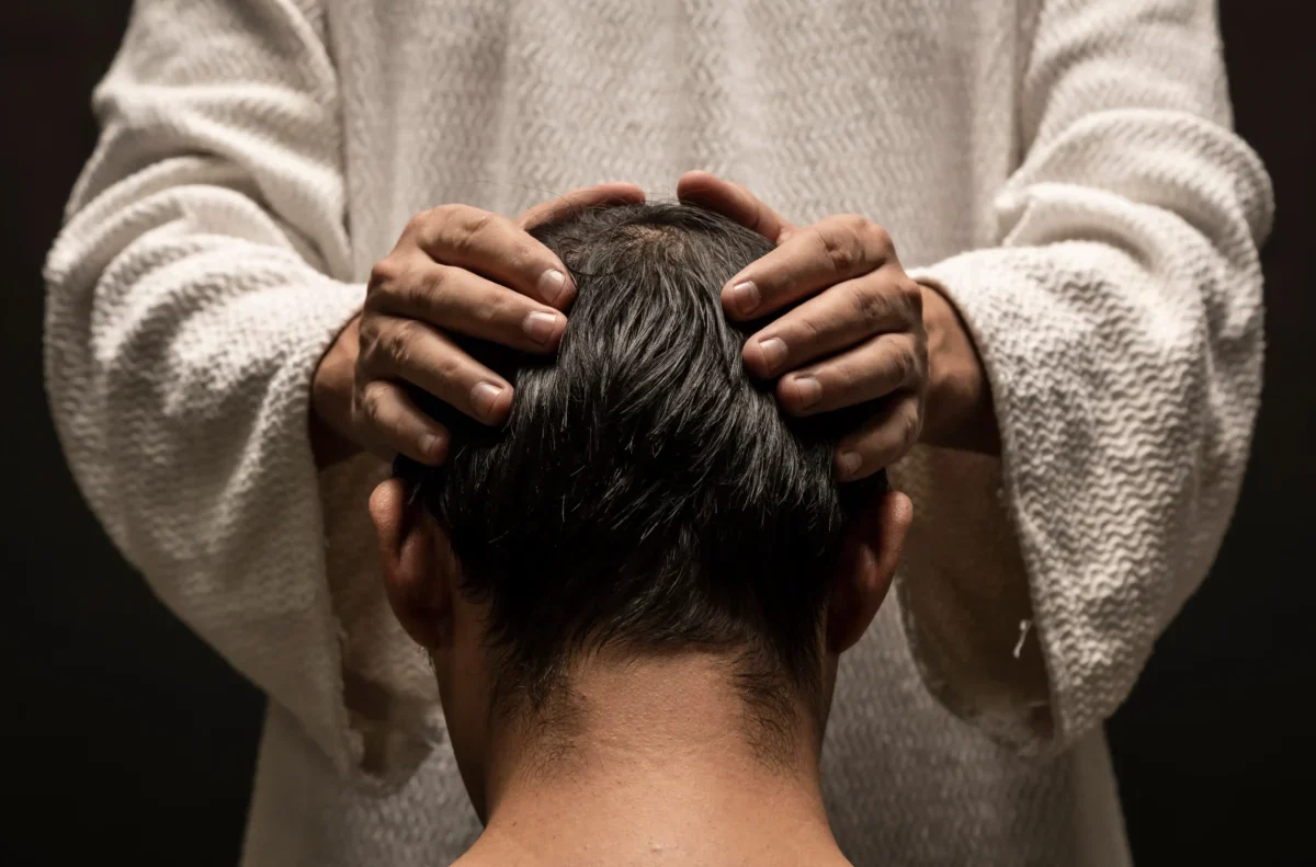 Muž drží chlapce na hlavě.