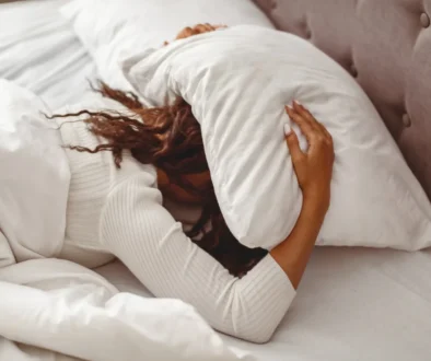 Žena si polštářem zakrývá hlavu.