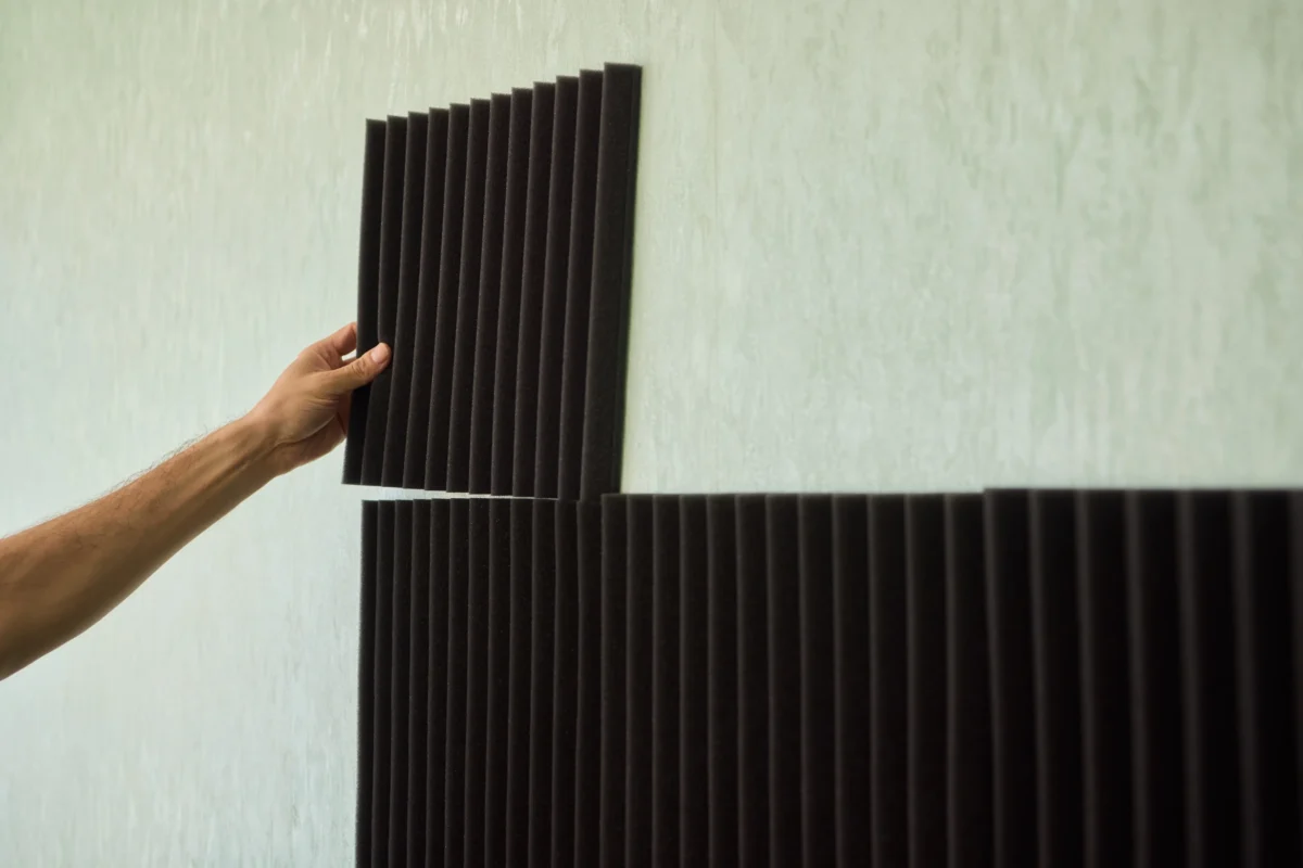 Člověk dává na stěnu akustickou pěnu.