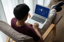 Muž má na klíně notebook s AI.