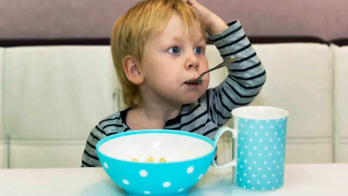 Chlapeček sedí a má v puse lžičku.