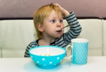 Chlapeček sedí a má v puse lžičku.