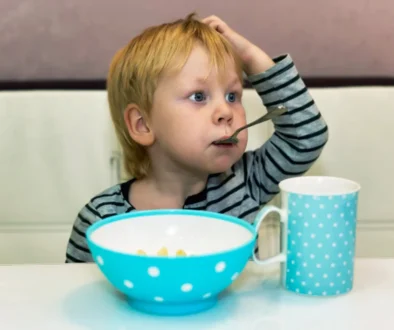 Chlapeček sedí a má v puse lžičku.