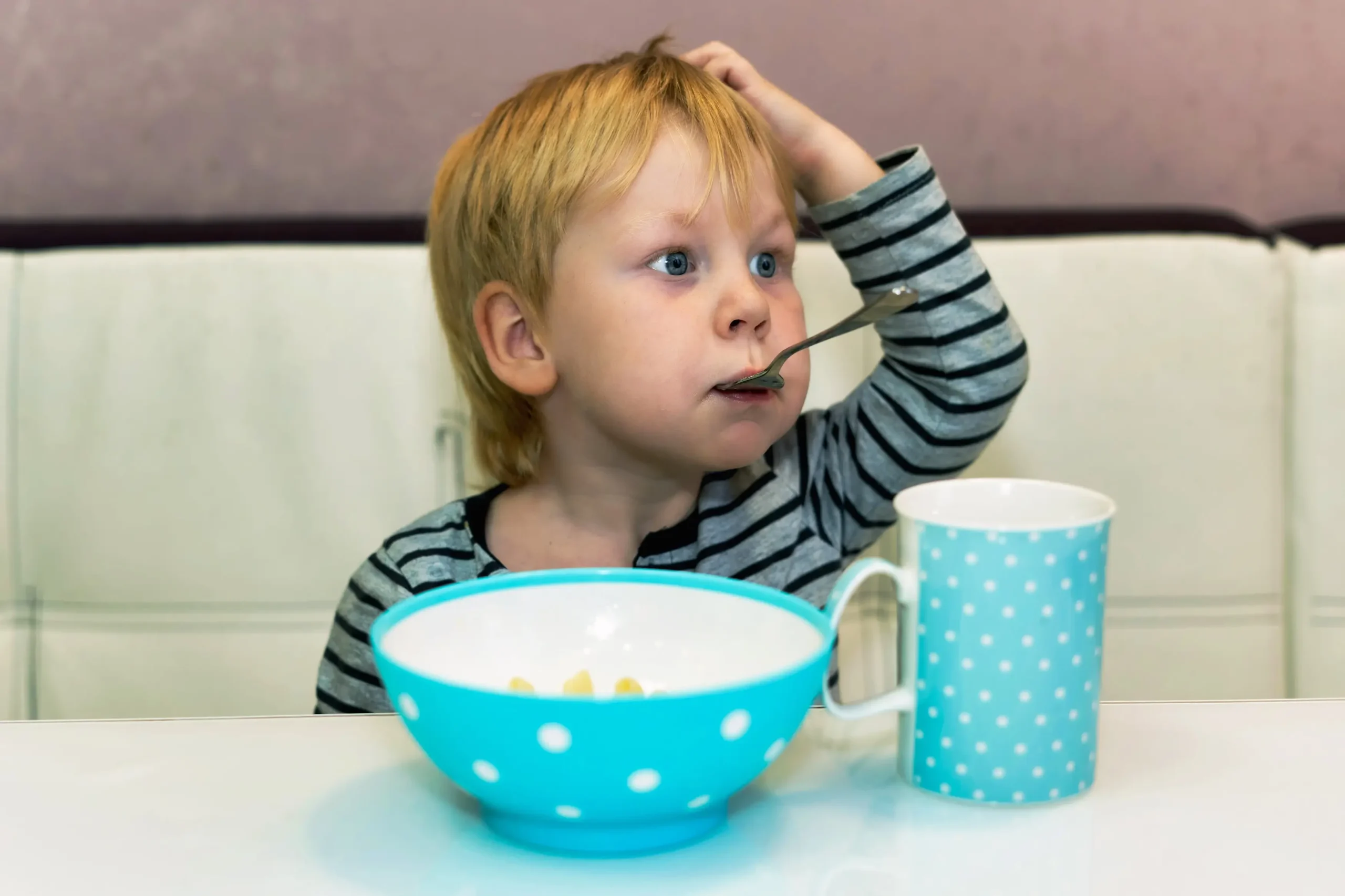 Chlapeček sedí a má v puse lžičku.