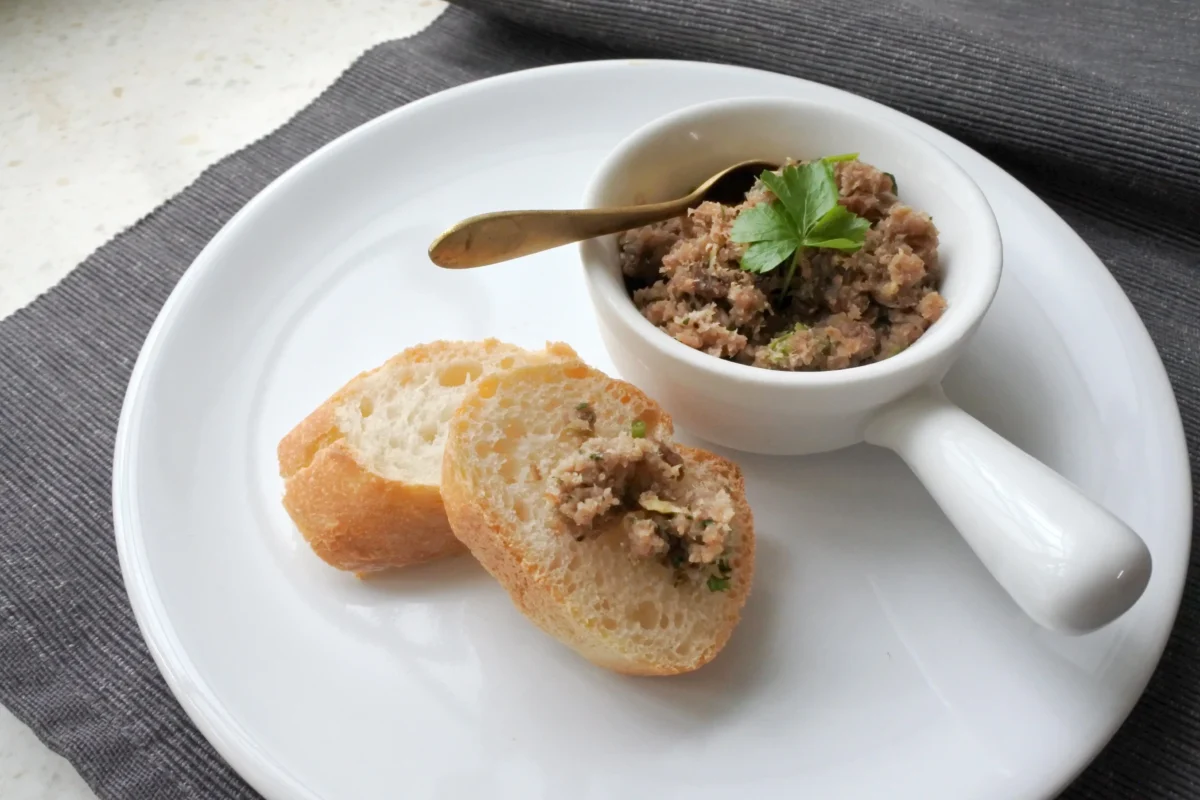 Na talíři je bagetka a škvarková pomazánka. 