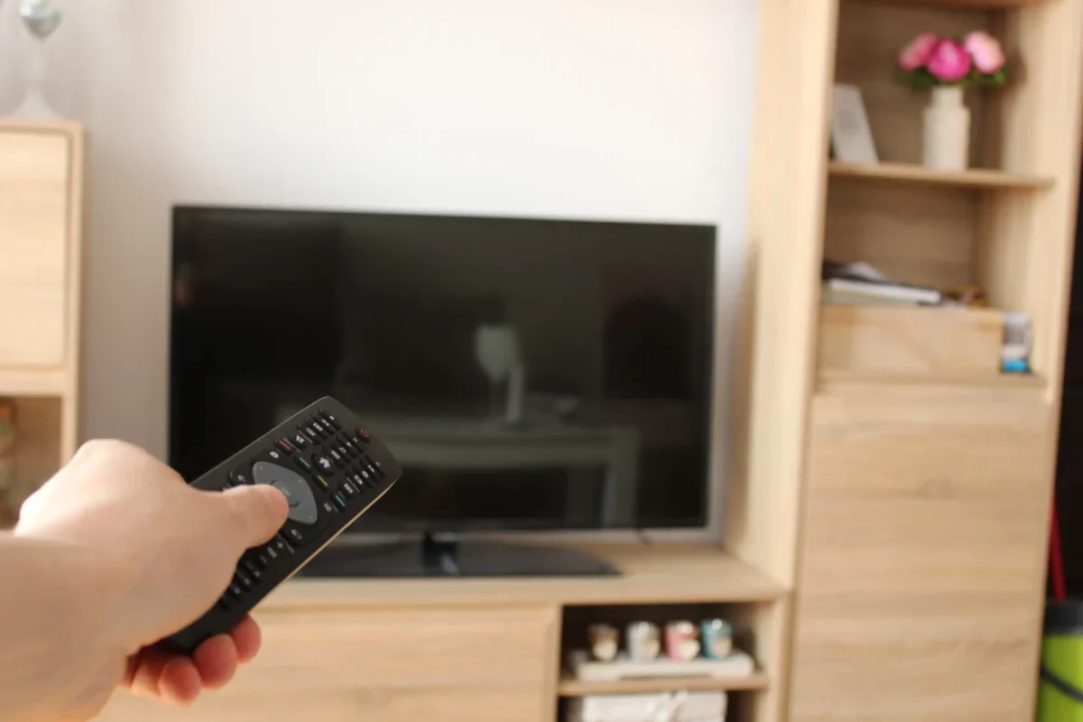 Člověk ovladačem míří na TV.