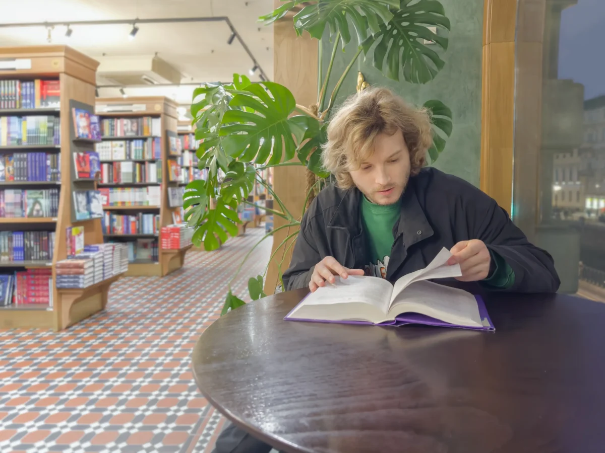 Muž si v knihovně čte.