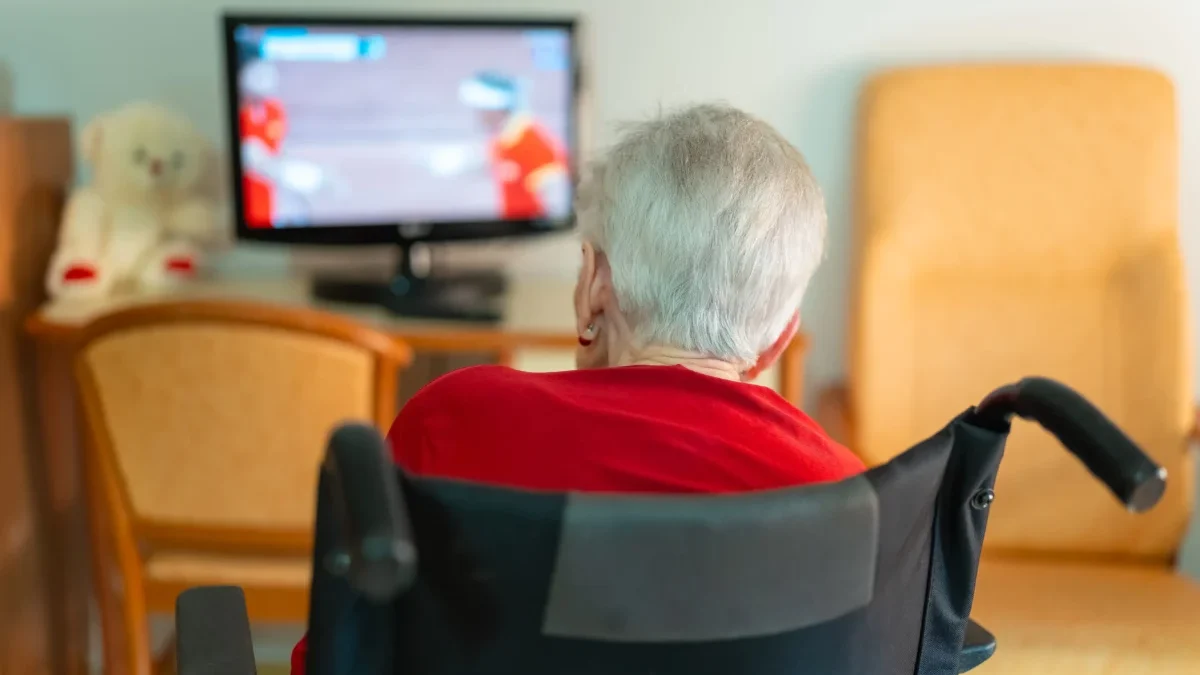 seniorka na vozíku sleduje televizi
