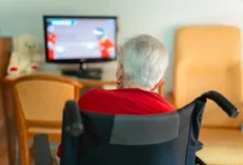 seniorka na vozíku sleduje televizi