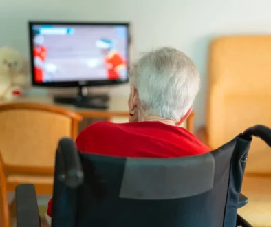 seniorka na vozíku sleduje televizi