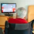 seniorka na vozíku sleduje televizi