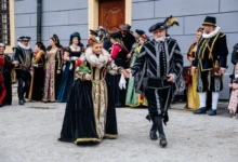 Dobově oblečení herci kráčí po nádvoří.