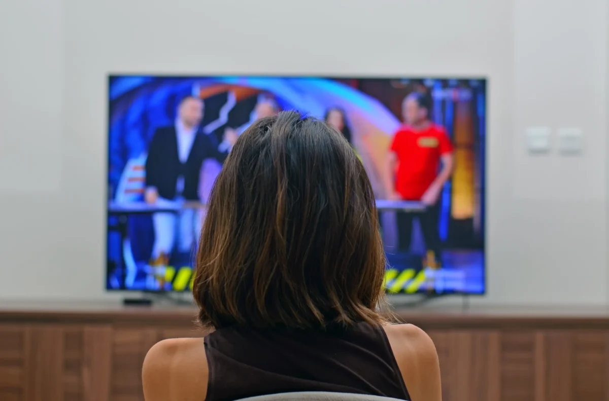 Žena sedí před televizí.