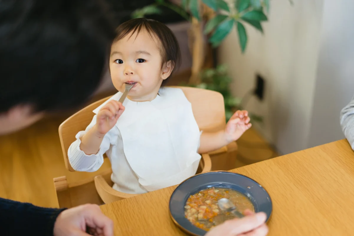 Japonské dítě sedící u stolu s jídlem.