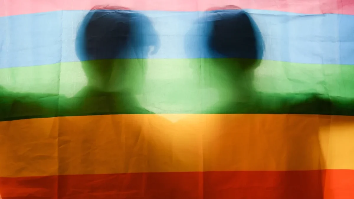 Muži stojí za duhovou vlajkou.