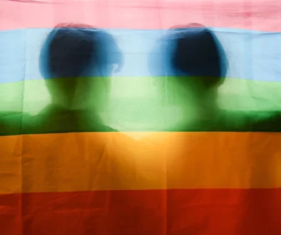 Muži stojí za duhovou vlajkou.