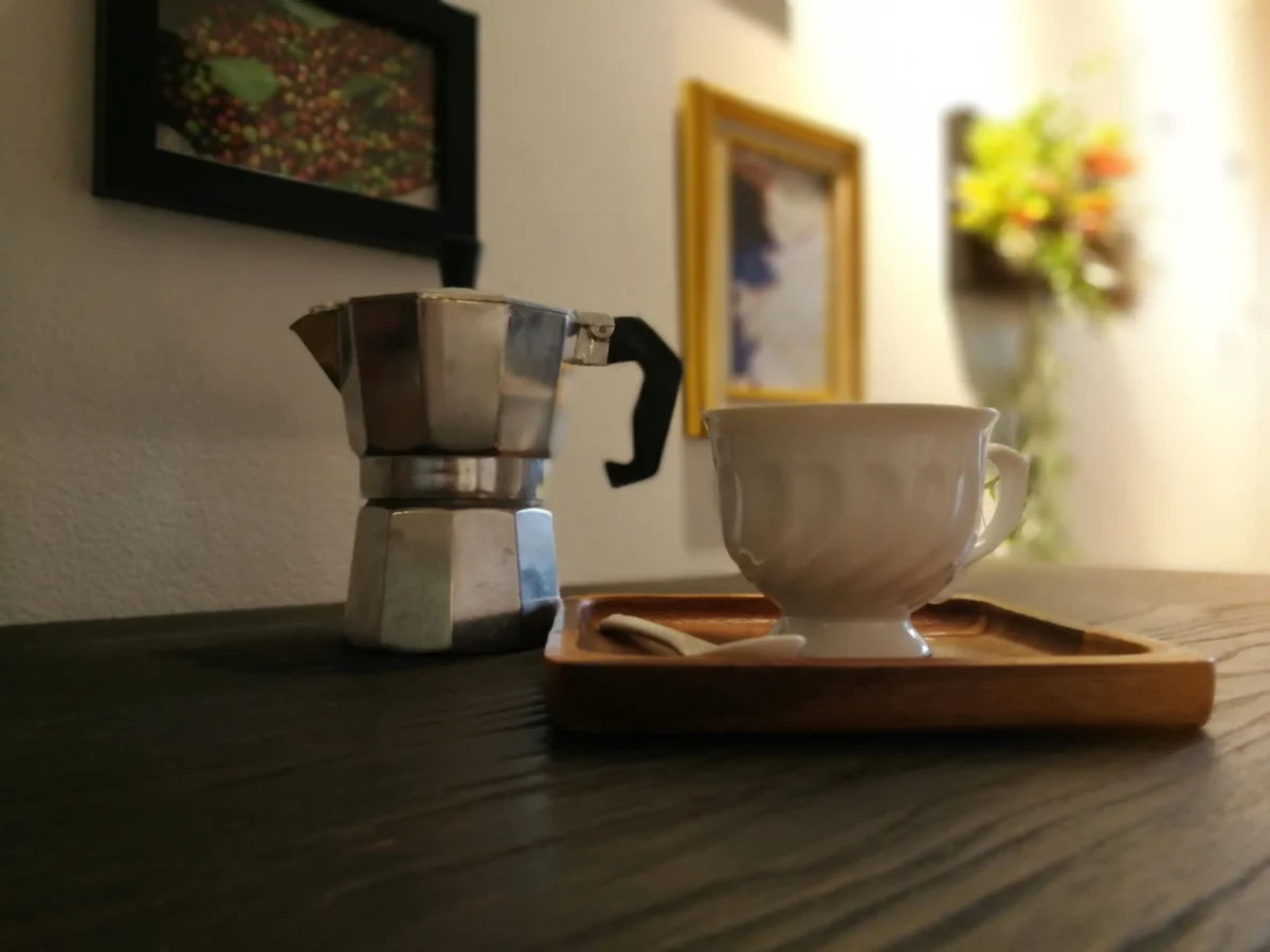 Vedle hrnku stojí moka konvička. 