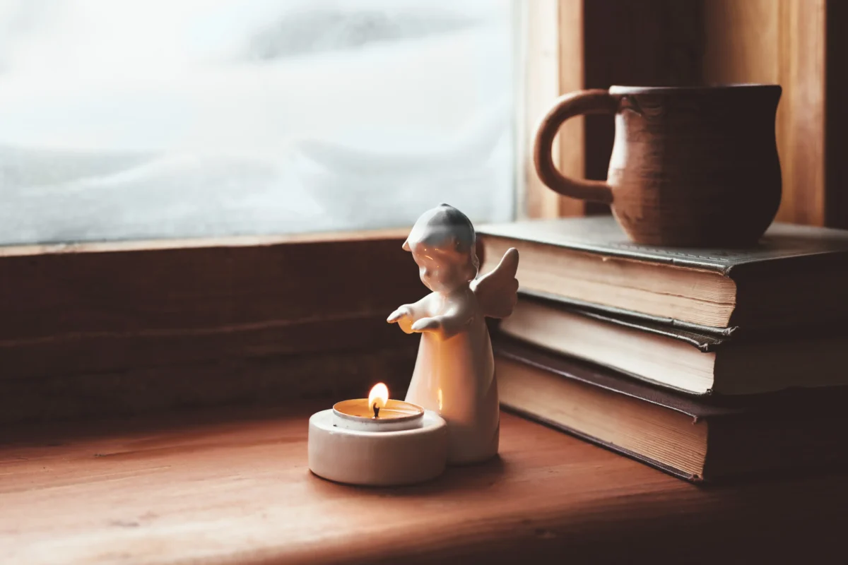 Na parapetu je andělíček, knížky a hrnek. 