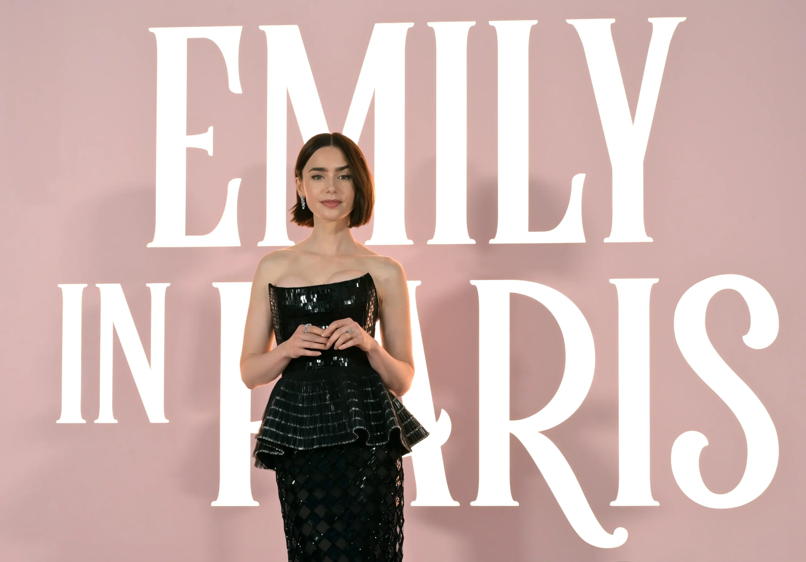 Lily Collins stojí u nápisu Emily in Paris.