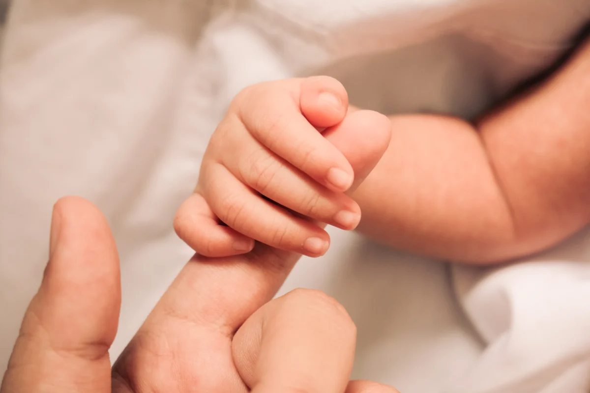 dítě drží prst dospělého