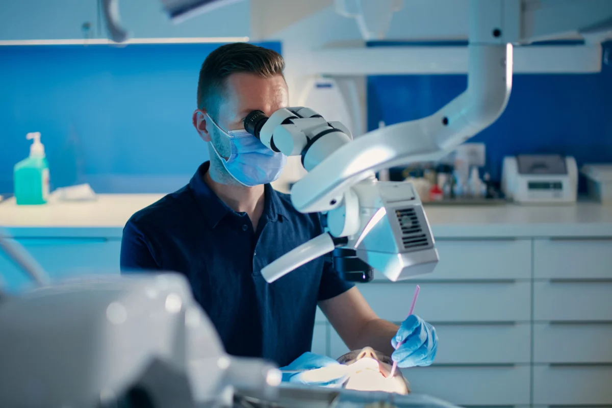 muž s rouškou kouká do mikroskopu