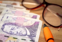 Na stole leží peníze, propiska a brýle.