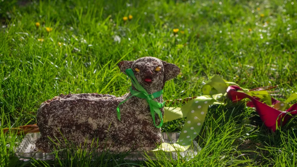 Na trávě leží velikonoční beránek.