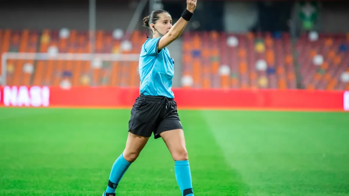 Rozhodčí v ruce drží kartu.