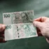Člověk v ruce drží české bankovky.