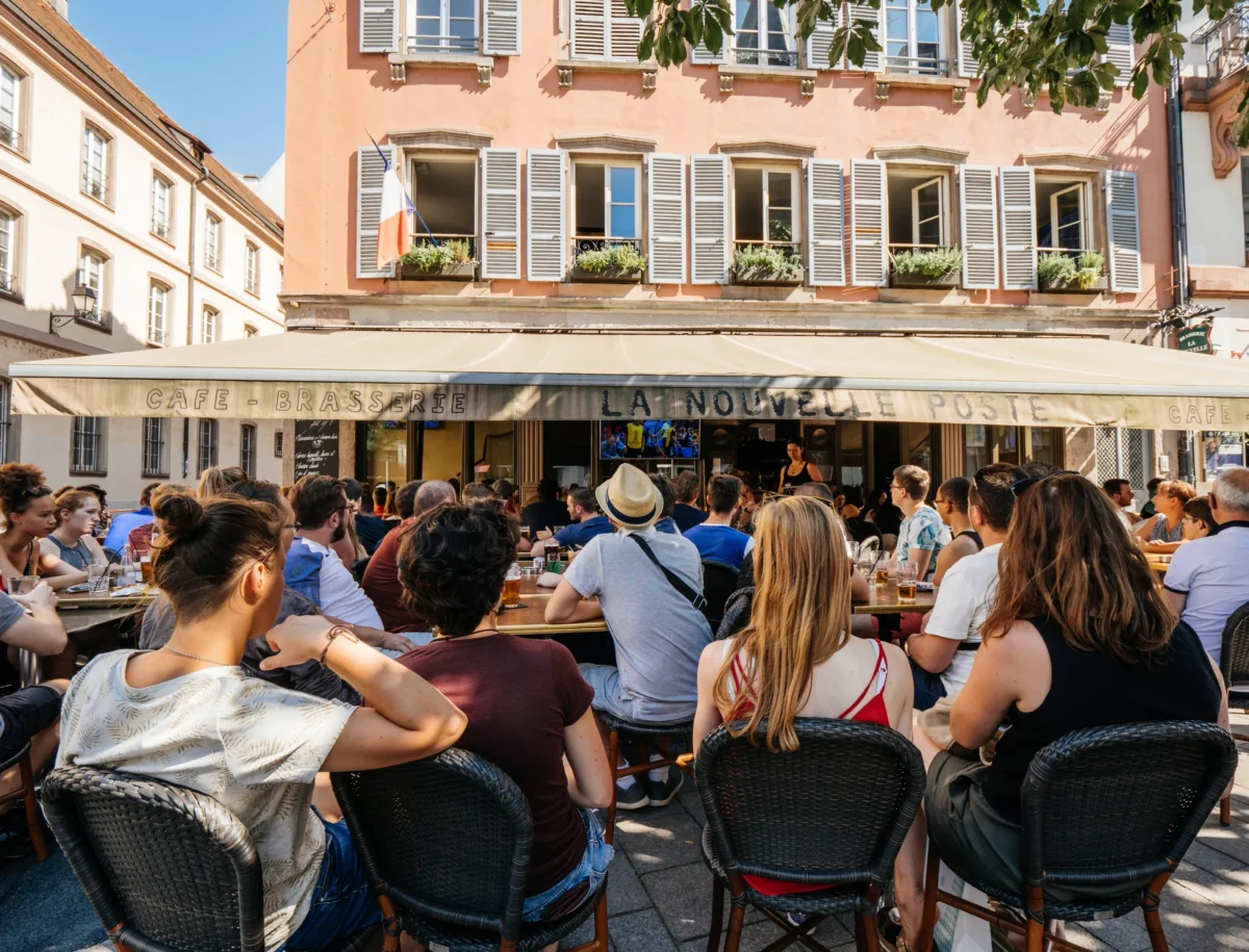 Lidé sedí na zahrádce restaurace. 