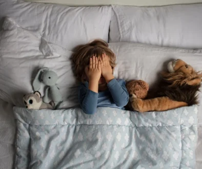 Chlapec leží v posteli a zakrývá si oči.