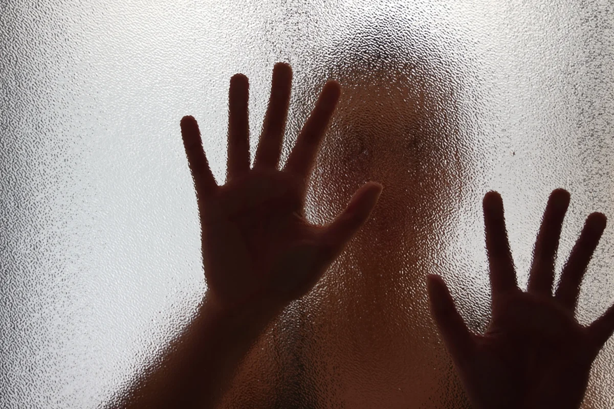 Ruce položené na skle dveří